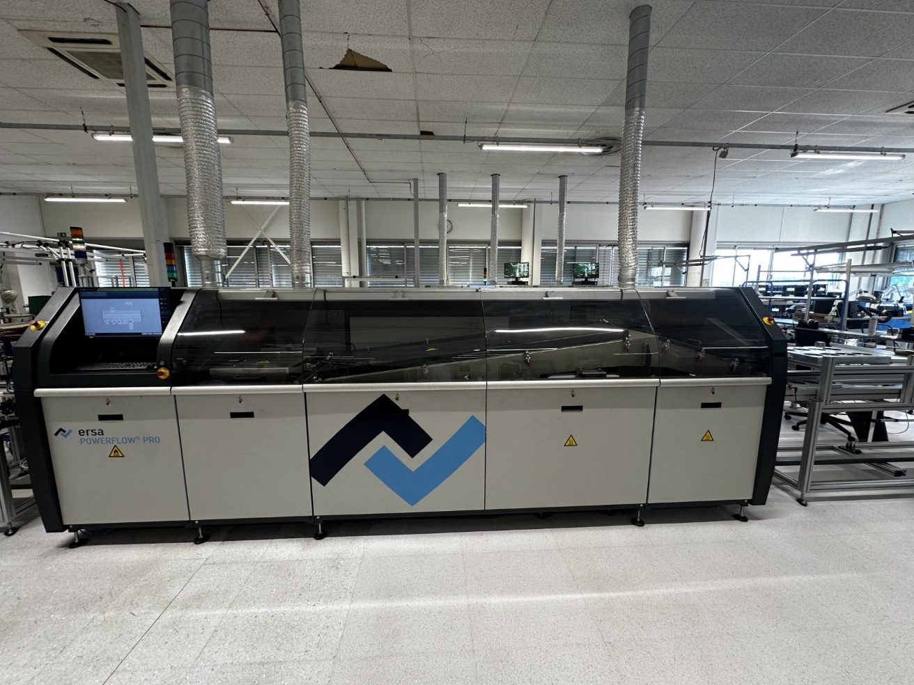 Machine de soudure à la vague, en sortie de laquelle la carte est chauffée